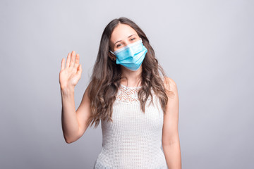 Portrait of young woman wearing medicinal mask and saying hello gesture.
