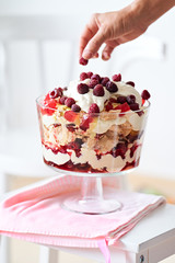 hand decorating trifle cake with berries