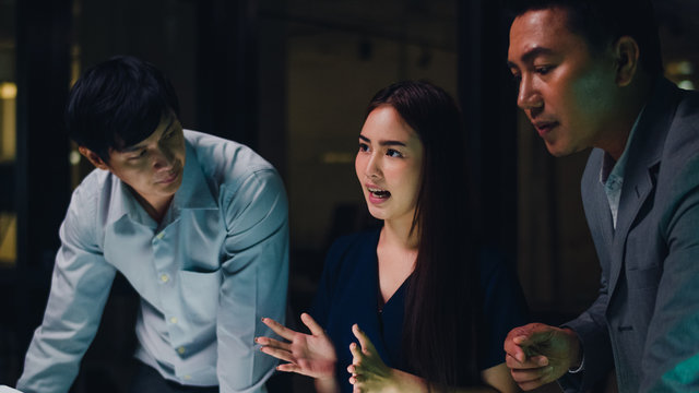 Millennial Asia businessmen and businesswomen meeting brainstorming ideas about new paperwork project colleagues working together planning success strategy enjoy teamwork in small modern night office.