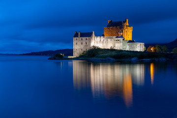 Eilean Donan Castle in Scottish highlands with water reflection photographed at blue hour after sunset
