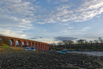 Fototapeta na wymiar The Brick Built Railway Bridge over the South Esk River at the Montrose Basin, with Fishing Boats lying on the muddy shore at low tide.