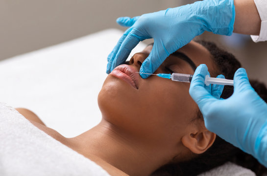 Black lady getting lip filling injection at beauty salon