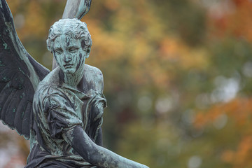 Statue of ancient beautiful winged angel in downtown park of Potsdam in beginning of Autumn at sunset, Germany