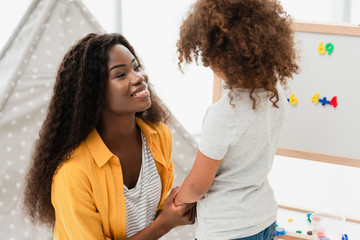 african american mother and daughter holding hands at home