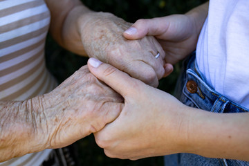 Hands of an elderly man in the hands of a young man close-up.