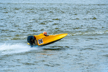 Yellow powerboat with number 26 go fast along the lake