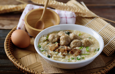 Asian food, Rice soup with meat ball, grilled mushroom and vegetable in a bowl on woven bamboo tray