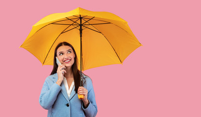 Portrait of smiling young girl holding umbrella talking on phone