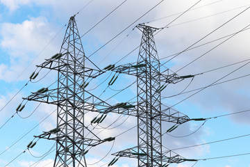 High voltage towers with electrical wires on blue sky with white clouds. Electricity transmission...