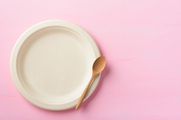Biodegradable plate, Compostable plate or Eco friendly disposable plate and wooden spoon on pink background