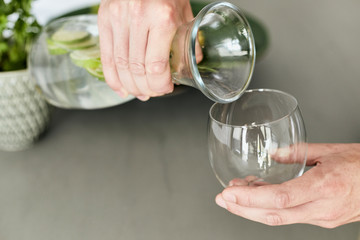 Person, die sich Wasser/Hausgemachte Limonade aus einer Karaffe in ein Glas schüttet