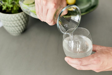 Person, die sich Wasser/Hausgemachte Limonade aus einer Karaffe in ein Glas schüttet