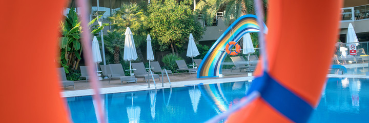 Obraz na płótnie Canvas large orange lifebuoy hotel water pool background view from round hole