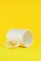White porcelain mug as close-up, on yellow background. Space for text.