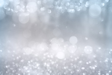 Obraz na płótnie Canvas Bokeh effects on silver glittering background White bokeh effects on blue and silver glittering abstract background with rays of light. Background for wedding and christmas. Space for design and text.