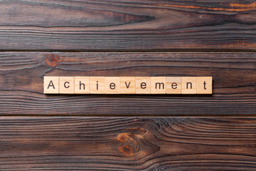 achievement word written on wood block. achievement text on table, concept