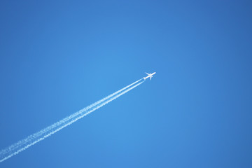 Trail of jet plane on clear blue sky. Airplane flying with white contrail