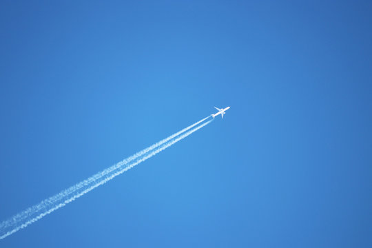 Trail Of Jet Plane On Clear Blue Sky. Airplane Flying With White Contrail