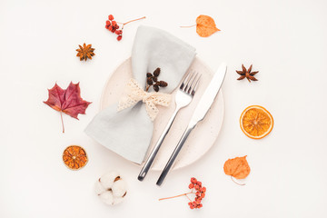 Thanksgiving autumn background. Plate with Cutlery and napkin decorated with autumn leaves, berries and spices. Top view.