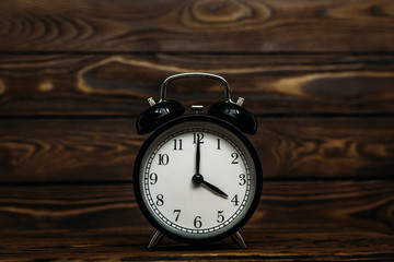 Clock on a wooden background. The clock shows the time of four o'clock in the afternoon. The clock...
