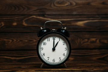 Clock on a wooden background. A clock showing the time of one o'clock. Clock showing the time of...