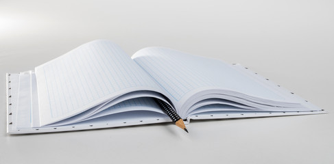 Expanded checkered notebook with open sheets and pencil. Selective focus. Blurred background.