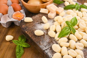 Fototapeta premium Gnocchi with potatoes. Traditional italian food from Rome, Sardinia, south of italy. Homemade gnocchi with parmesan, egg, cornmeal (semolina). On a wooden table. High quality photo. Above. Copy space 