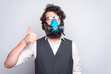 Photo of business man in suit showing thumbs up and wearing respirator.
