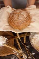 Serving fresh natural bread against a background of ears of flour and wooden planks