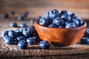 Freshly picked blueberries in a bowl. Fresh and healthy juicy blueberries on a rustic background. Blueberries as a fruit antioxidant symbol. Concept for healthy eating and nutrition.