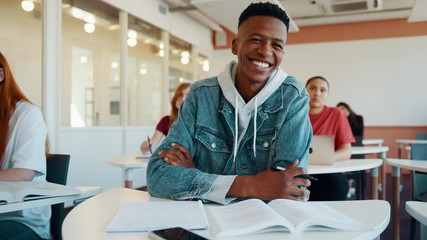 Male student smiling during the lecture in high school classroom. African student attending the lecture in university.
 - Powered by Adobe