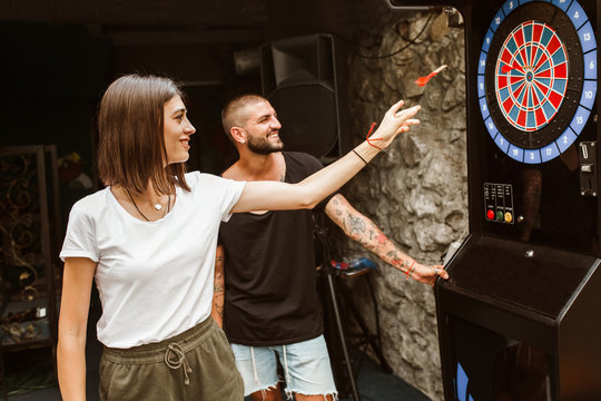 Young couple flirting and playing darts