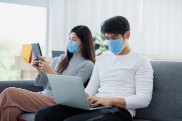 Asian men work attentively through Modern Technology phone and wear a mask to protect against viruses. Concept of working at home