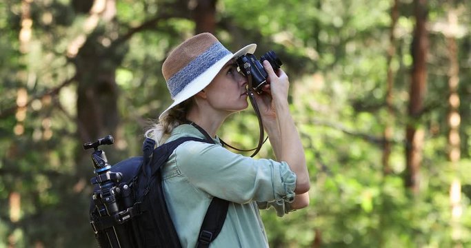 nature photography - woman photographer taking picture of  with analog film camera in forest