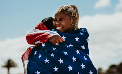 American female athletes with flag hugging each other after a wi
