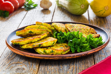 Zucchini pancakes with parsley on a plate on a wooden table