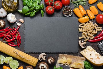 Italian food ingredients over black stone background. 