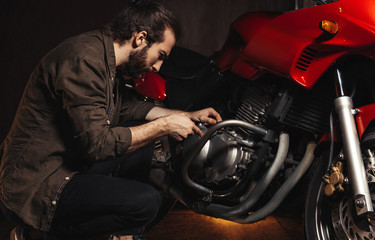 Man with a beard repairing his motorcycle in the garage