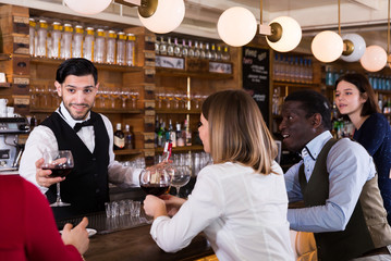 Young people are relaxing near bar counter and drinking alcohol in luxurious restaurant.