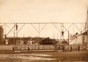 Quilha do dirigível Pax fora do hangar de Vaugirard, na França, com operários dispostos na estrutura semirrígida.