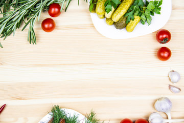 Composition with pickled cucumbers on the white plate,  tomatoes, garlic, dill, parsley, rosemary. Cooking food background with free space for text. Top view with copy space