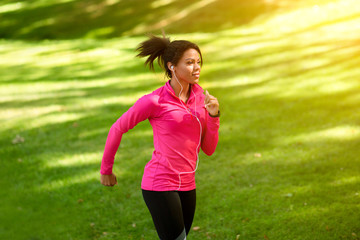 Athletic black girl jogging by public park