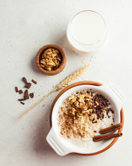 Oatmeal porridge with nuts, cinnamon and chocolate, a glass of milk. Breakfast, healthy food. Copy space. Good morning.