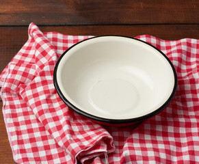 empty round metal white plate stands on wooden brown table