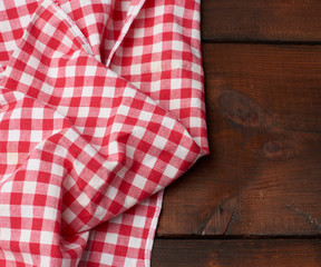 red-white textile kitchen towel on a brown wooden background from old boards