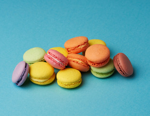 stack of multi-colored round baked macarons cakes on a blue background