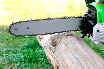 Chainsaw and log on a background of green grass. Side view.