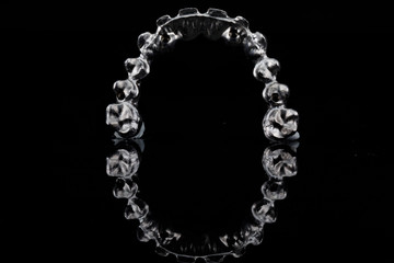 titanium bar in the form of an arc for creating a permanent upper jaw prosthesis made of metal ceramic, filmed on black glass with reflection © Dental Pro Content
