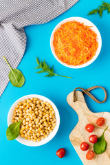 Vegetarian meal. Chickpeas and carrot in bowls on blue table top view