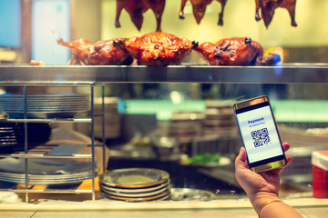 Selective focus to smartphone in hand to show QR code tag with blurry roast duck in in a Chinese restaurant to accepted generate digital pay without money. Qr code payment concept.
